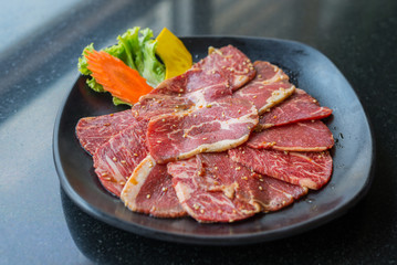 Raw beef slice for barbecue or Japanese style yakiniku on black
