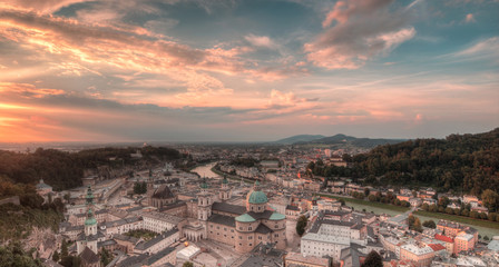 Fototapeta premium Aerial panoramic view of the historic city of Salzburg with Salzach river in beautiful golden evening light with blue sky and clouds at sunset in summer, Salzburger Land, Austria