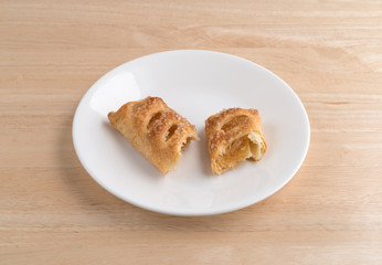 Apple fruit tart broken on a plate atop a wood table.