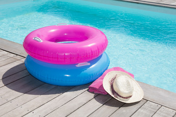 Colorful towel and blue and pink buoy near the pool - obrazy, fototapety, plakaty