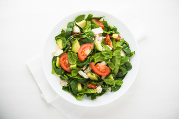 Fresh salad with chicken, tomatoes, spinach and avocado on white wooden background top view. Healthy food.