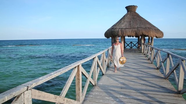 Woman walks down pier at tropical resort