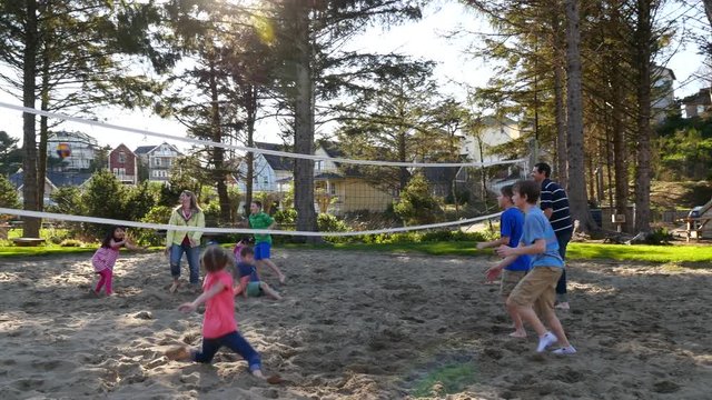 Family Playing At Sand Volleyball Court