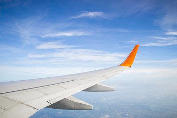Obraz premium Wing of a plane and blue sky with cloud
