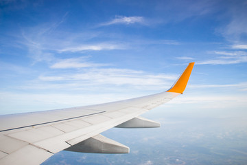 Fototapeta premium Wing of a plane and blue sky with cloud