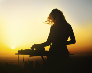 Silhouette of a woman dj at sunset - obrazy, fototapety, plakaty