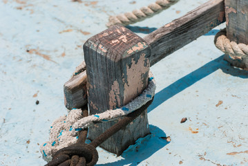  old wooden fishing boat cleat with rope wrapped around.