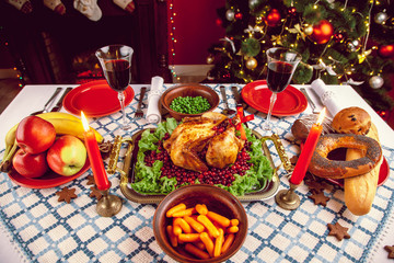 Christmas dinner by candlelight, table setting. Thanksgiving table with baked turkey in a decorated room with a Christmas tree.