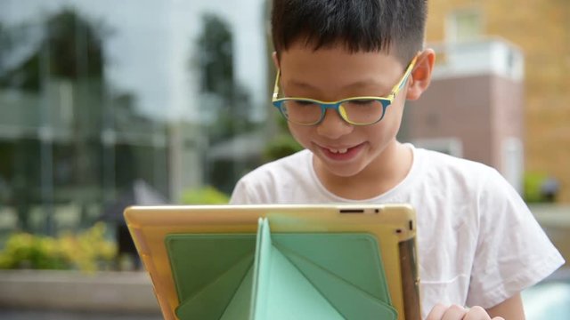 Cute asian boy playing games on tablet computer 
