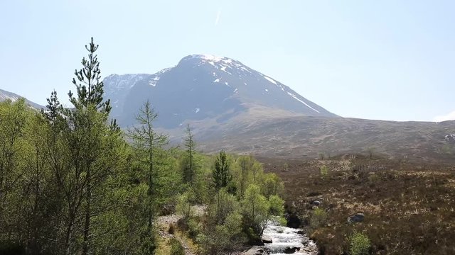 Ben Nevis Scotland UK with snow topped mountains with mountain stream in foreground