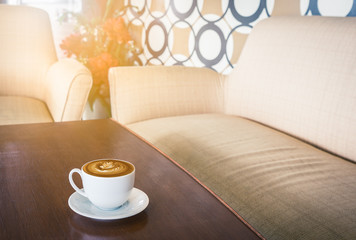 Fototapeta na wymiar latte art coffee on table in retro style coffee house with morning sunlight, vintage tone