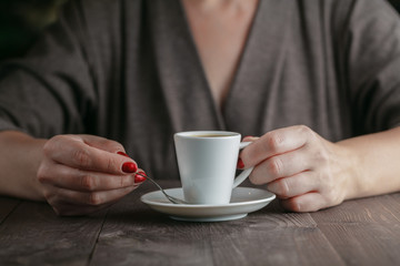 woman hands with espresso on a wood table