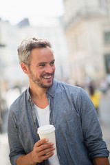 man walking on the streets with a take away coffee at hand