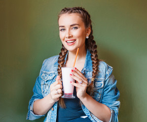 Beautiful girl with braids sitting in a cafe and drinking a milkshake, smiling at the camera