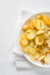 Fried potatoes with rosemary in plate. Overhead view.