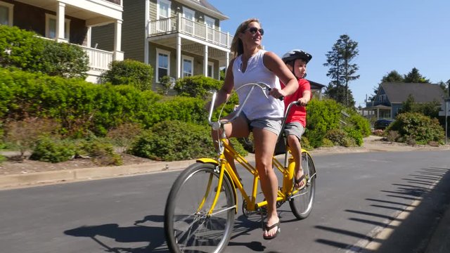 Mother and son riding tandem bicycle together in coastal vacation community