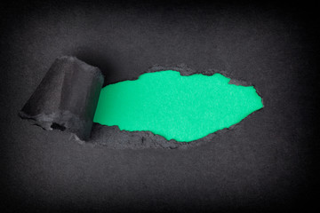 Green paper background appearing behind torn black paper