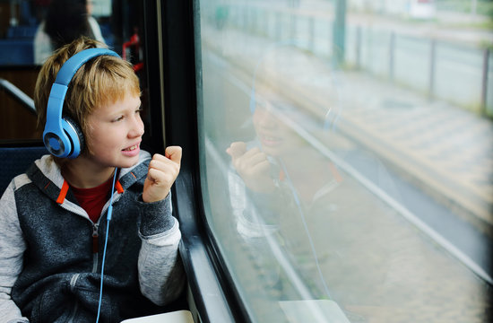 Cute 8 years old boy looking through the window in the train