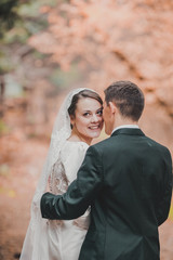 young family, the wedding, the newlyweds. Bride and groom walk around the trees in an autumn forest