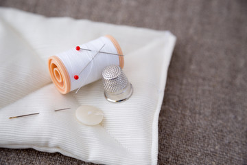 Spoletta bianca con ditale, spilli, ago e bottone