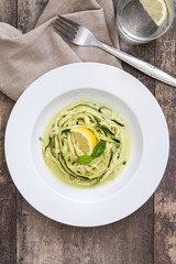 Zucchini noodles with pesto sauce on wooden background

