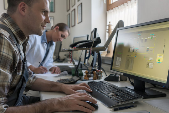 Man and woman in control room of water purification plant monitoring the technical processes