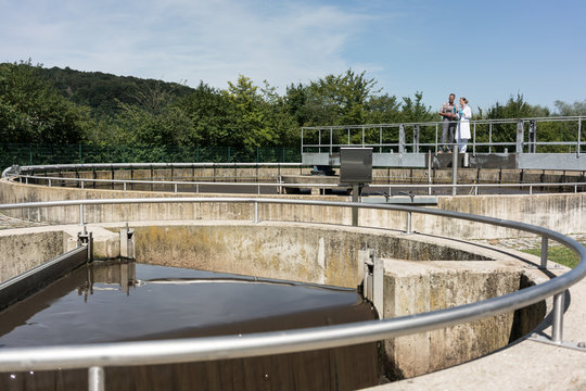 Wastewater treatment plant - man and woman standing at sedimentation tank