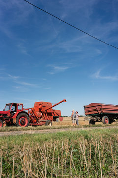 Farmer with his tractor and combine trailer finishing harvest day