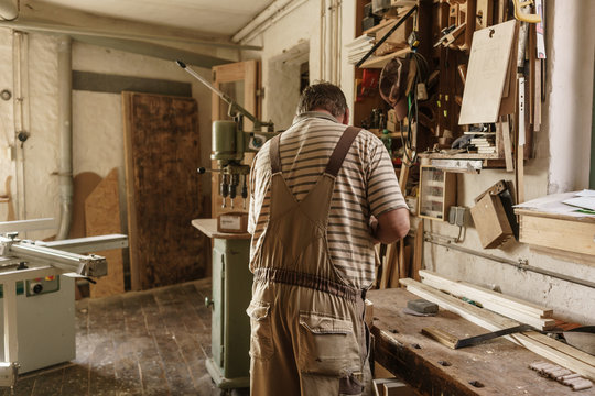 Carpenter at his workbench working on piece of wood with chisel