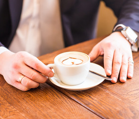 Man holding cup of coffee on wooden background
