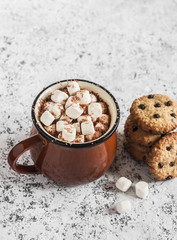 Hot chocolate with marshmallows and chocolate chips oatmeal cookies on a light background.