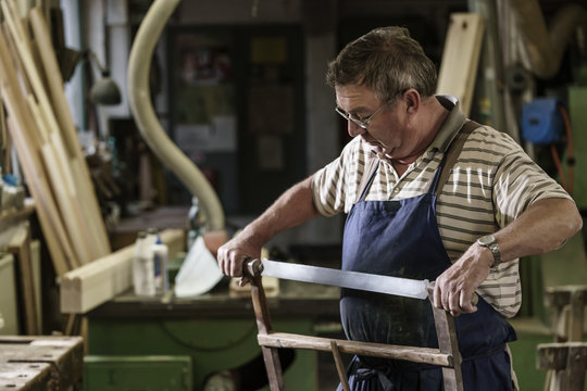 Craftsman in his wood workshop adjusting hacksaw