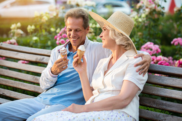 Couple with ice cream smiling. Adult man hugs lady. Pleasant conversation with friend. Romance of summer.