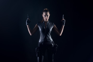 Fototapeta na wymiar Superhero woman in a leather catsuit holding guns