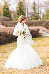 Fototapeta na wymiar Bride with bouquet posing in sunny autumn park