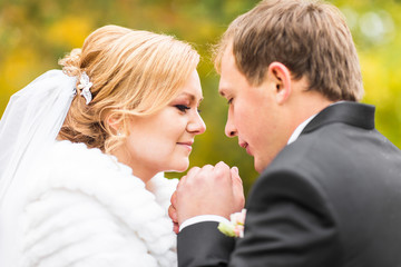 Close-up of bride and groom in autumn park
