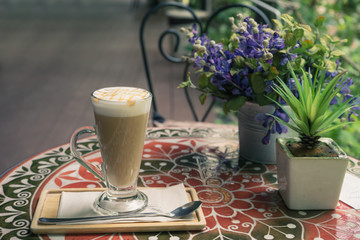 hot fresh coffee in white glass with silver spoon on wooden colorful table lavender flower at sunset at coffee time