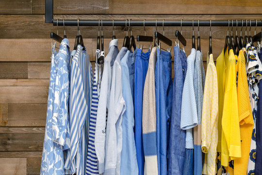 Multi-Colored Women's Clothing On Black Wooden Hangers. Blouses, Shirts, Trousers, Jackets.