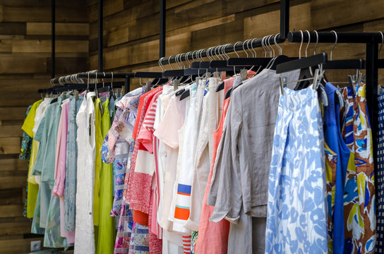 Multi-Colored Women's Clothing On Black Wooden Hangers. Blouses, Shirts, Trousers, Jackets.