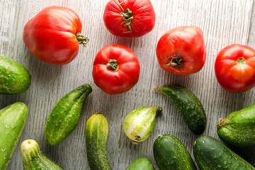 Healthy Food Background. Fresh Cucumbers and tomatoes on a wooden white table. Top view.