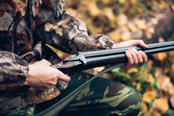 Male hunter in the autumn forest. A man holding a gun.