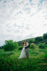 the bride and groom with a bouquet in the grass against the background mountain landscape