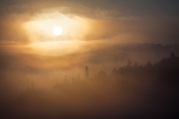 Fog over mountain range in sunrise light.