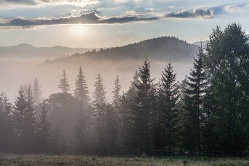 Fog over mountain range in sunrise light.