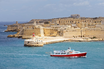 Fototapeta na wymiar Tourist ship sails in front of St. Elmo, Malta