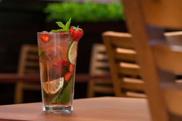 a cold drink with citrus and strawberries in a glass on the table