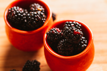Blackberries in a cup on blurred background of wooden planks