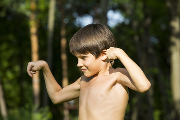 portrait of a boy in nature which shows his muscles