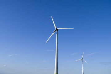 White windmills on blue sky background. Wind energy. 