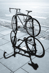 Hipster single gear fixie bicycle locked to a metal stand on a pavement